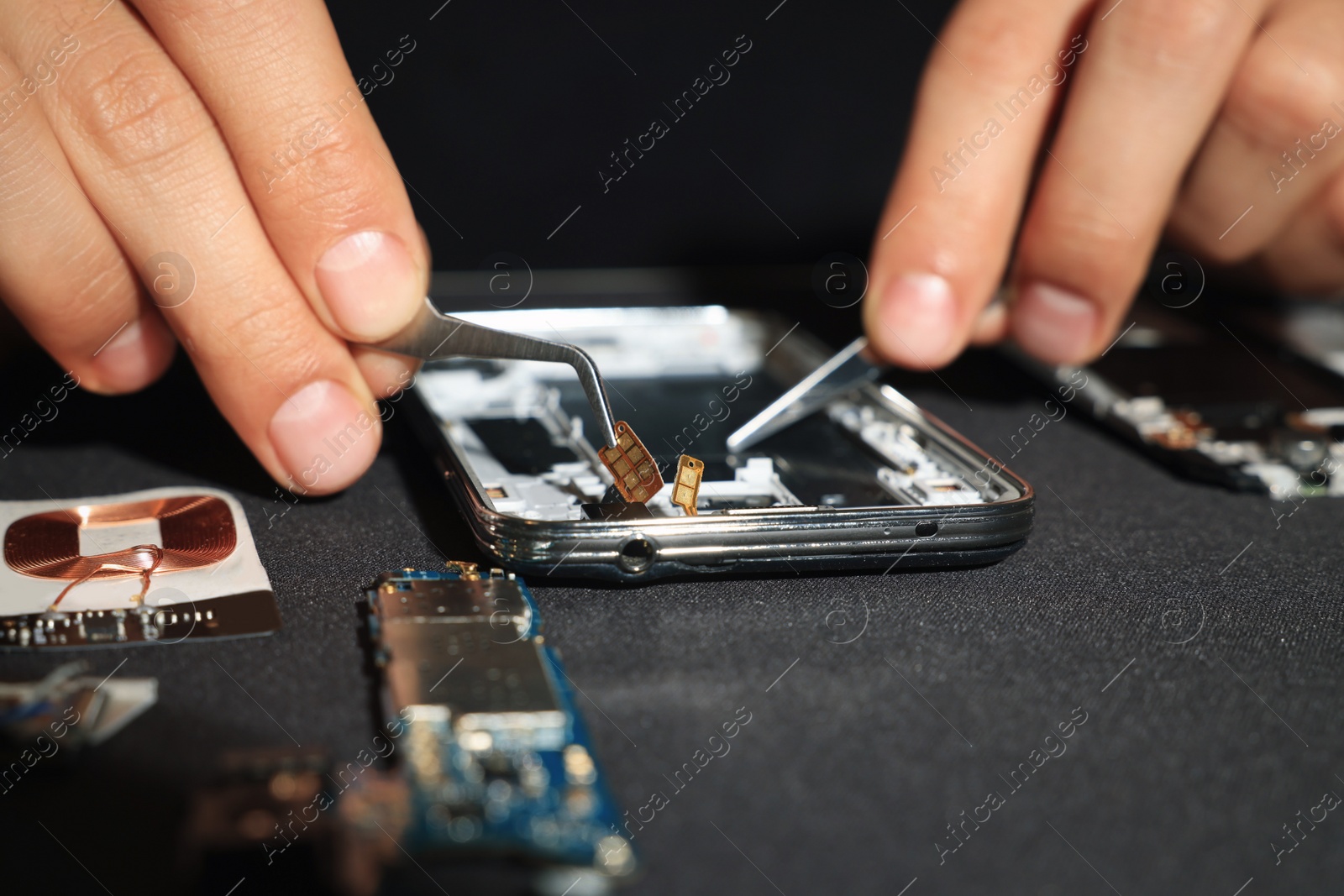 Photo of Technician repairing broken smartphone at table, closeup