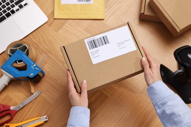 Post office worker packing parcel at wooden table, top view