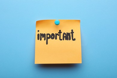 Photo of Paper note with word Important pinned on light blue background
