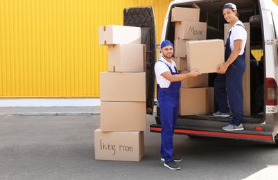 Male movers unloading boxes from van outdoors