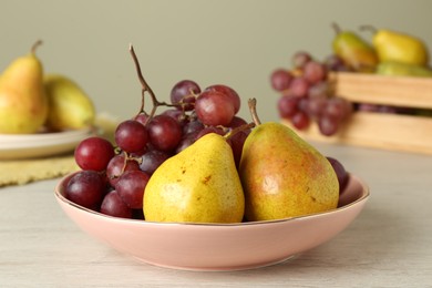 Photo of Fresh ripe grapes and pears on white wooden table