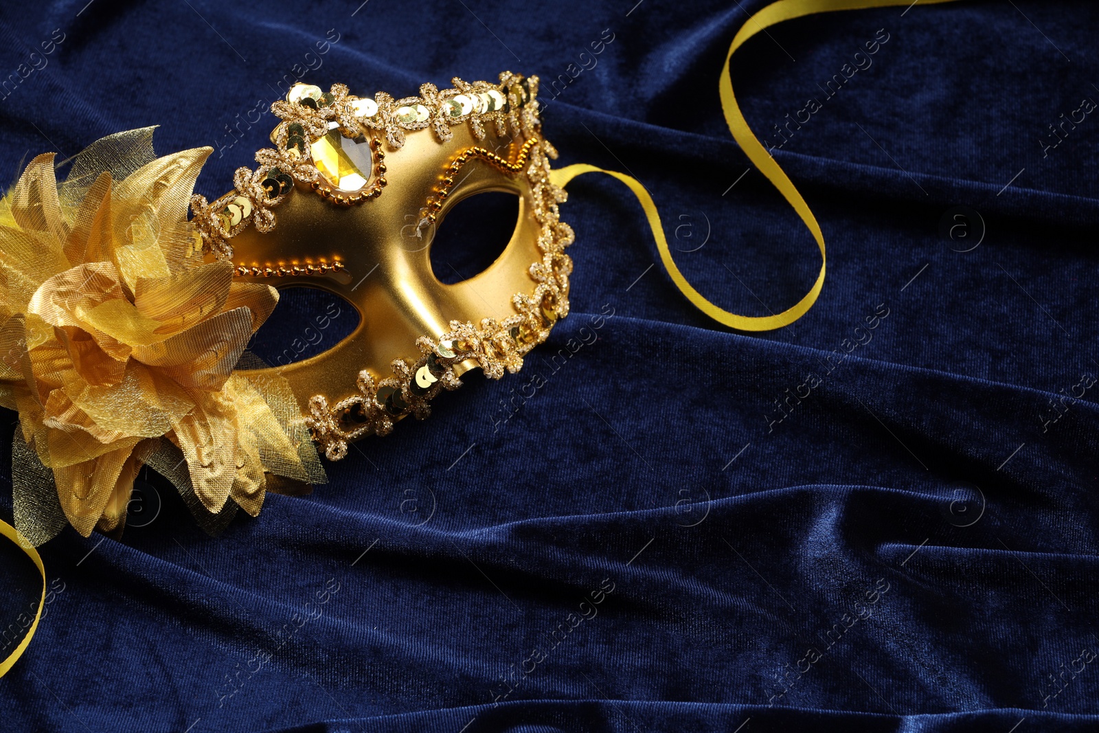 Photo of Theater arts. Golden venetian carnival mask on blue fabric, above view