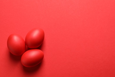 Photo of Flat lay composition of red dyed Easter eggs on color, space for text