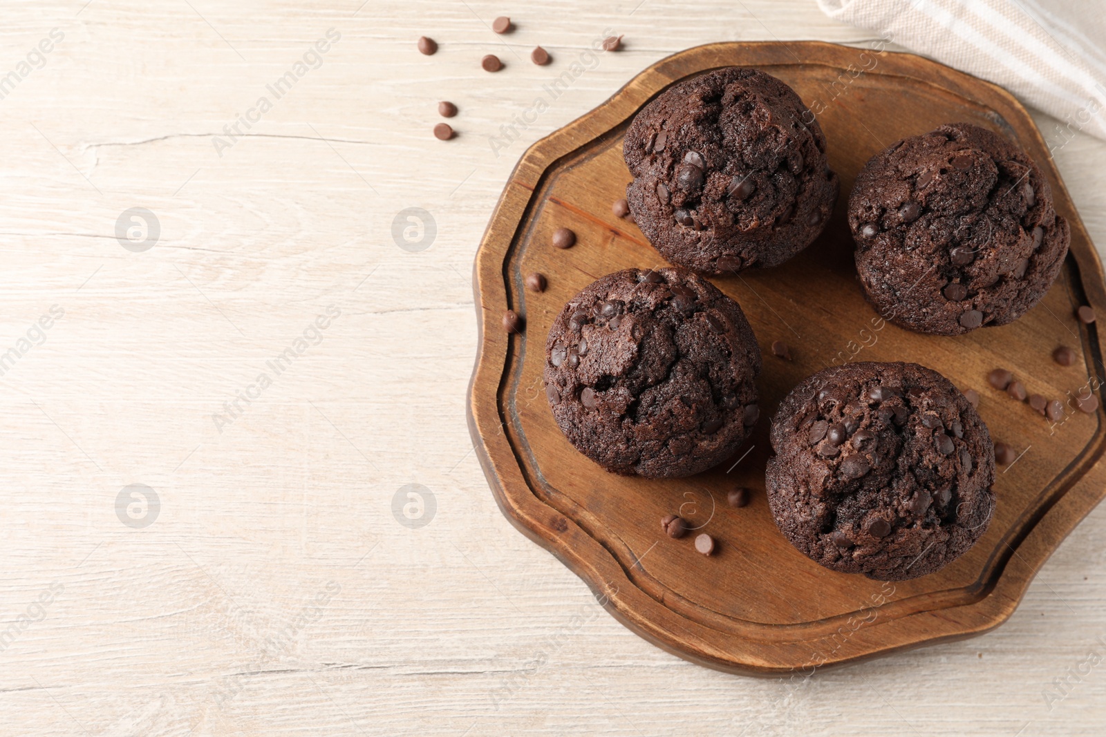 Photo of Delicious chocolate muffins on white wooden table, top view. Space for text