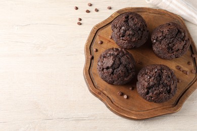 Photo of Delicious chocolate muffins on white wooden table, top view. Space for text