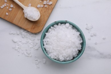 Photo of Bowl and spoon with pink sea salt on white marble table, flat lay