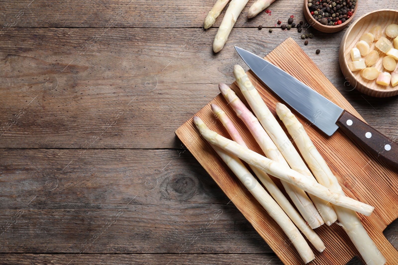 Photo of Fresh white asparagus, cutting board and knife on wooden table, flat lay. Space for text