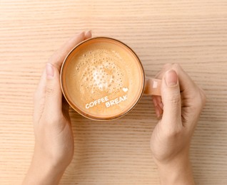 Coffee Break. Woman with cup of cappuccino at  wooden table, top view