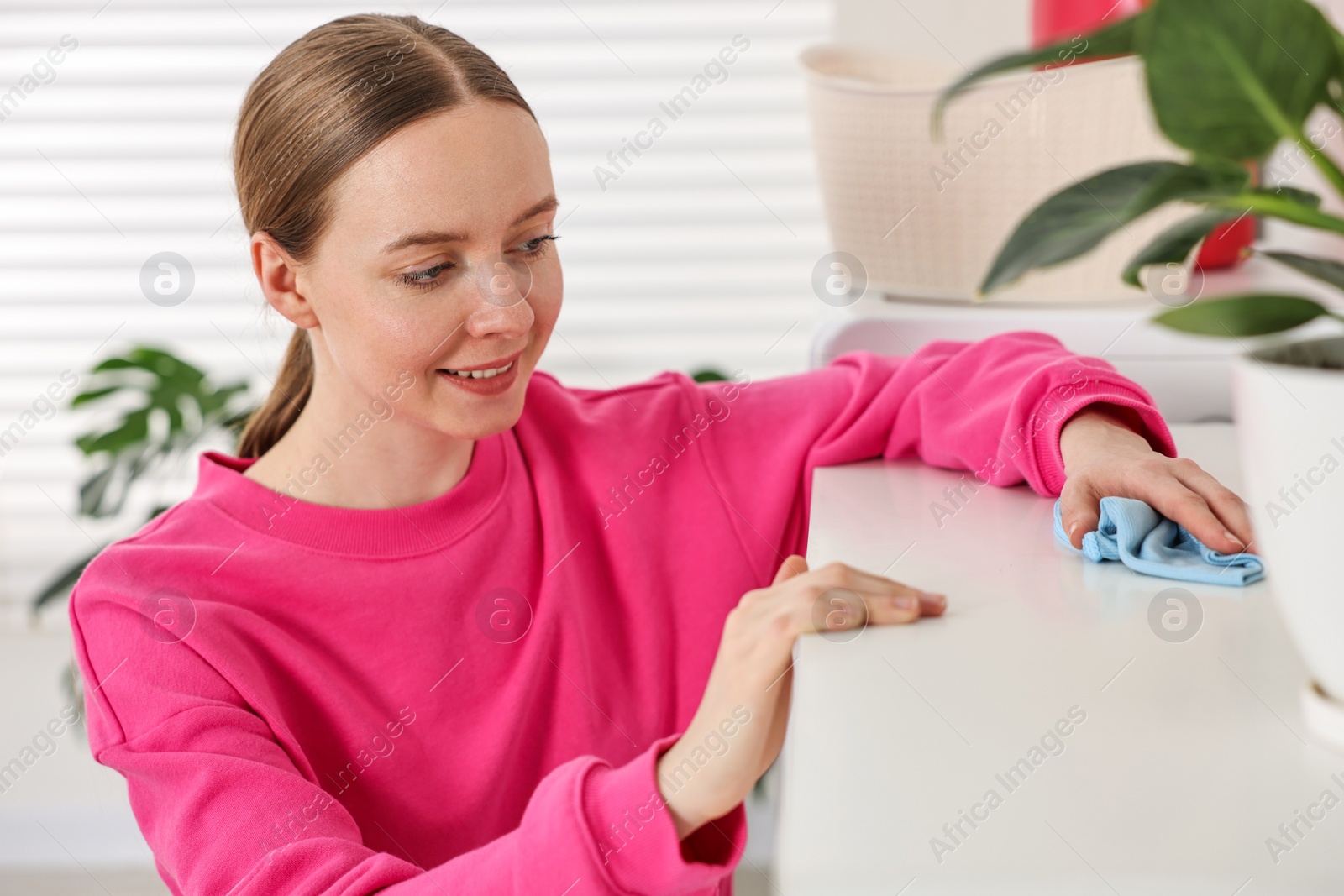 Photo of Woman cleaning furniture with rag at home