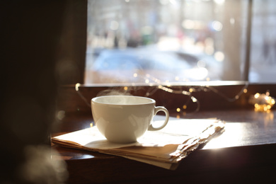 Photo of Delicious morning coffee and newspaper near window, indoors