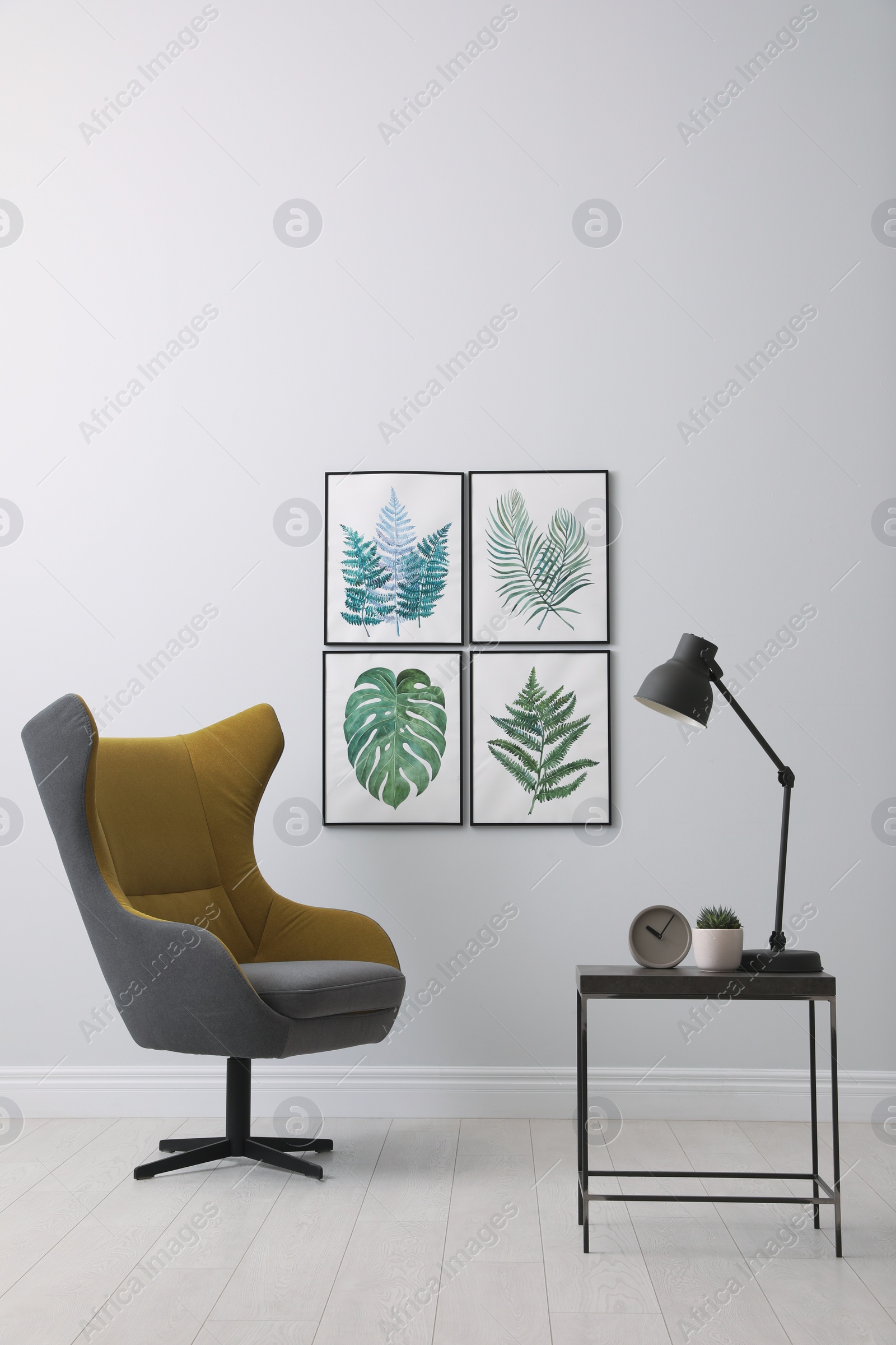 Photo of Stylish room interior with comfortable armchair and paintings of tropical leaves