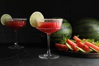 Photo of Cocktail glasses of delicious fresh watermelon juice with lime and sugar rim on black table