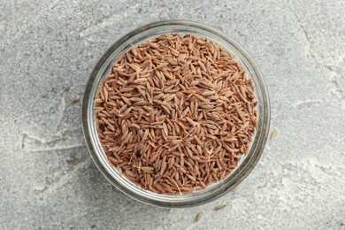 Bowl of caraway seeds on grey table, top view