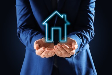 Mortgage rate. Man holding illustration of house on black background, closeup