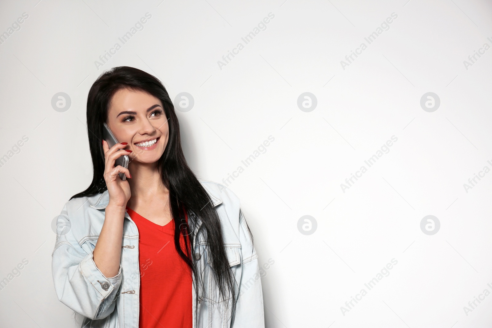 Photo of Portrait of stylish woman talking on phone against light background. Space for text