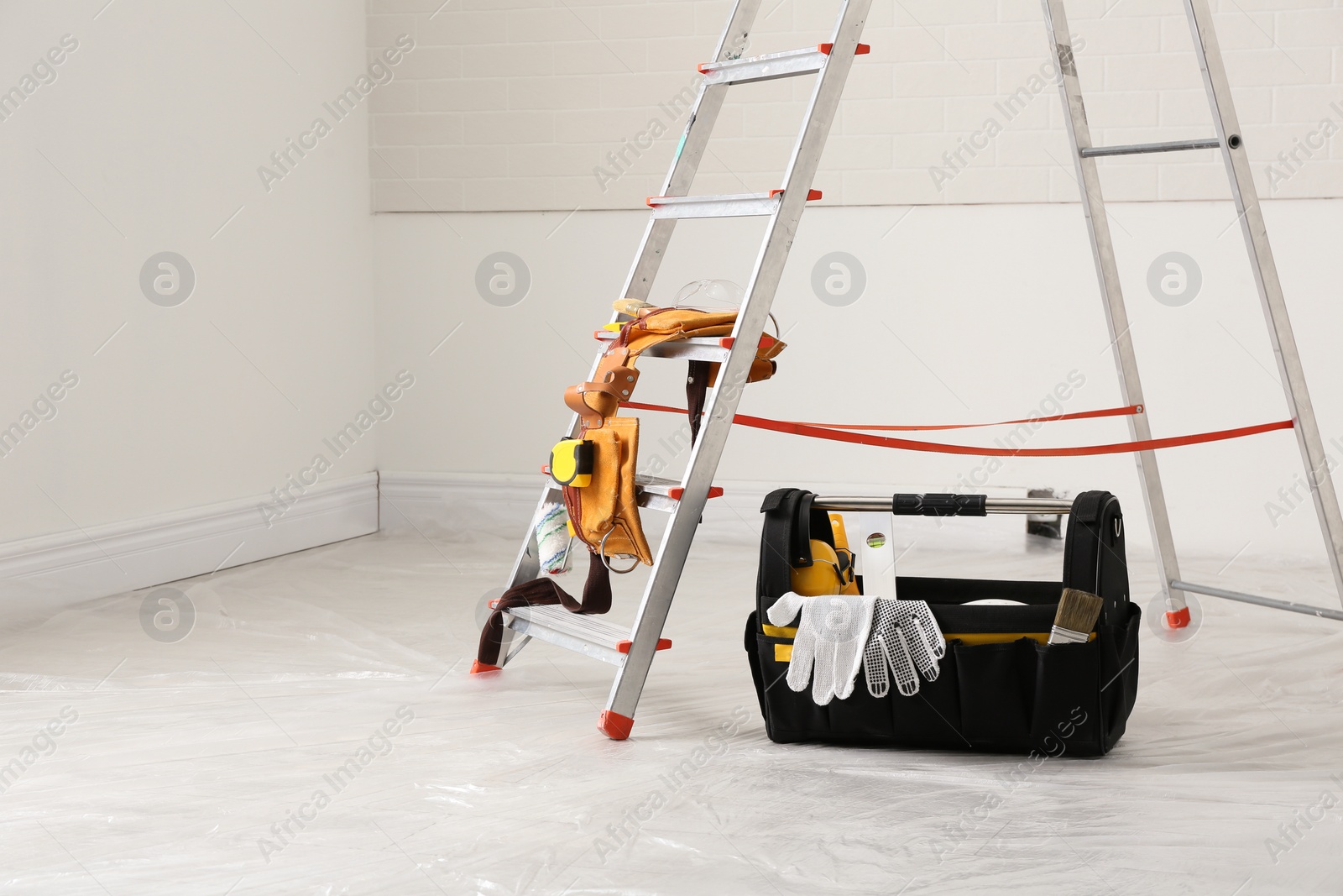 Photo of Stepladder and different tools near wall in room. Interior renovation