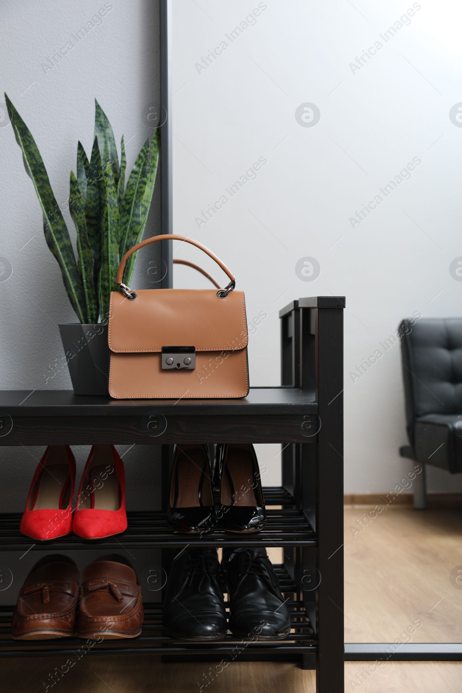 Photo of Shelving unit with stylish shoes and bag near grey wall in hallway