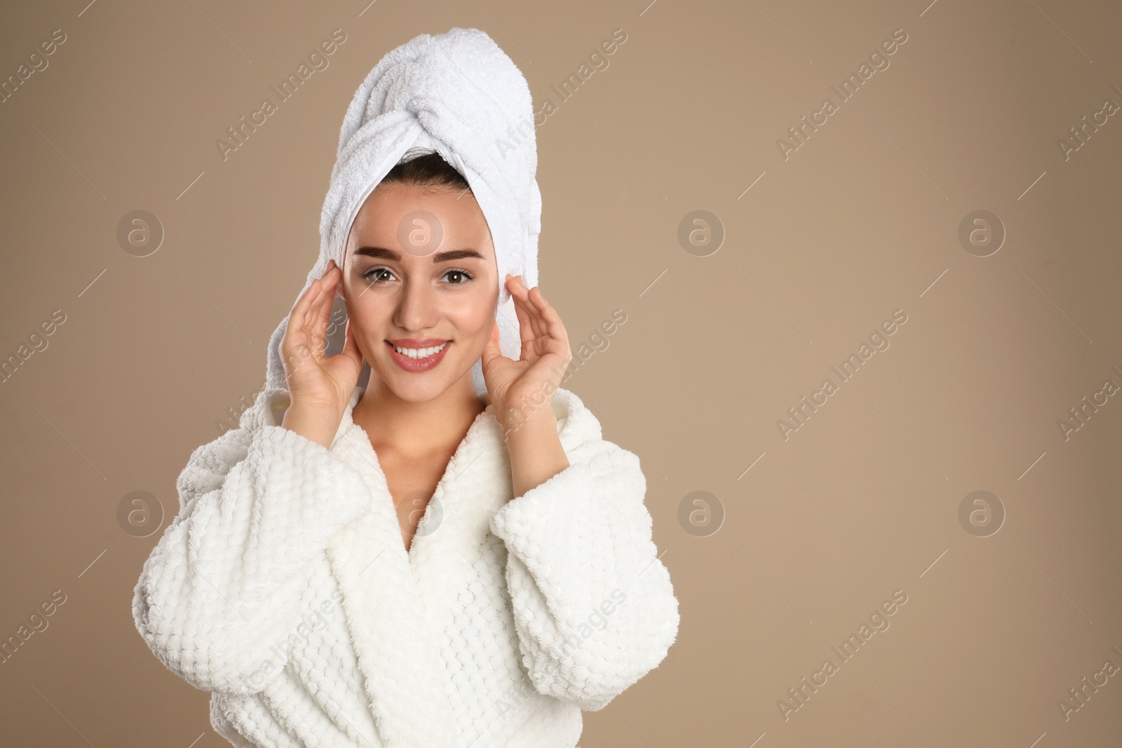 Photo of Beautiful young woman in bathrobe on brown background. Space for text