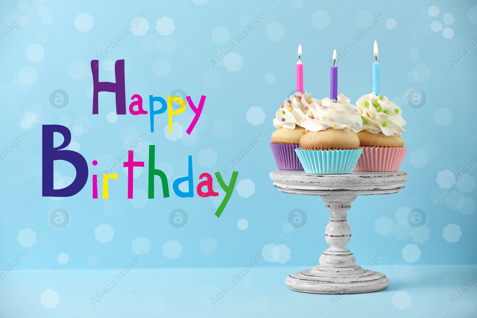 Image of Text Happy Birthday and delicious cupcakes with candles on light blue background