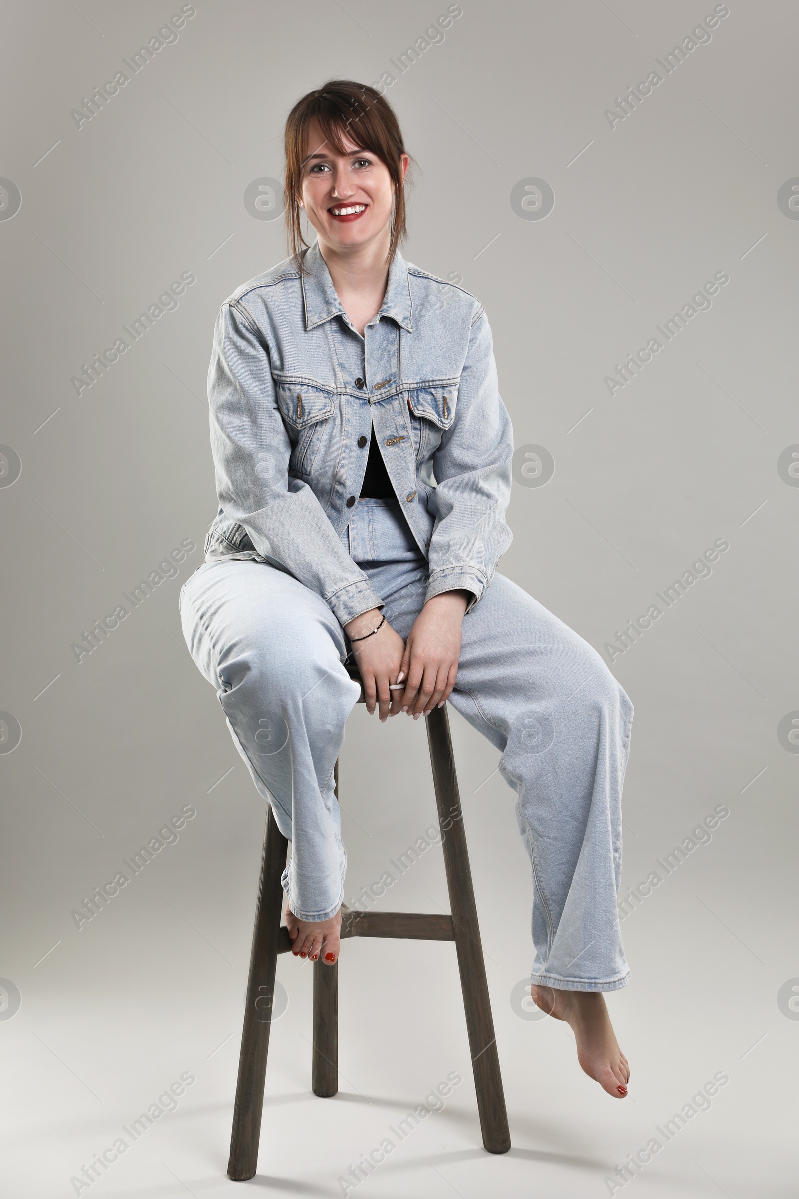 Photo of Beautiful woman sitting on stool against grey background