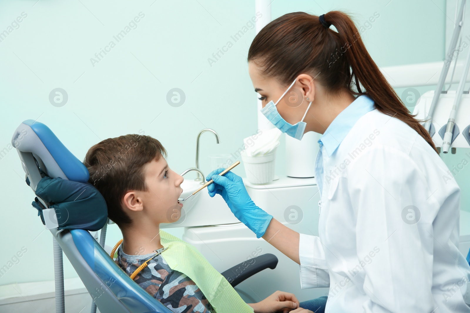 Photo of Professional dentist working with little patient in modern clinic