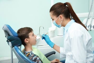 Photo of Professional dentist working with little patient in modern clinic