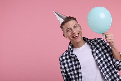 Photo of Happy man in party hat with balloon on pink background. Space for text