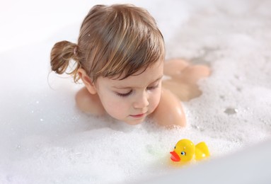 Photo of Little girl bathing with toy duck in tub