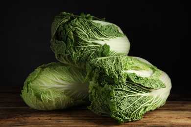 Photo of Fresh ripe Chinese cabbages on wooden table against black background