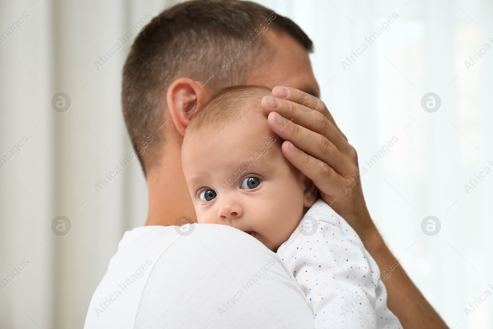 Photo of Father holding his cute baby on blurred background