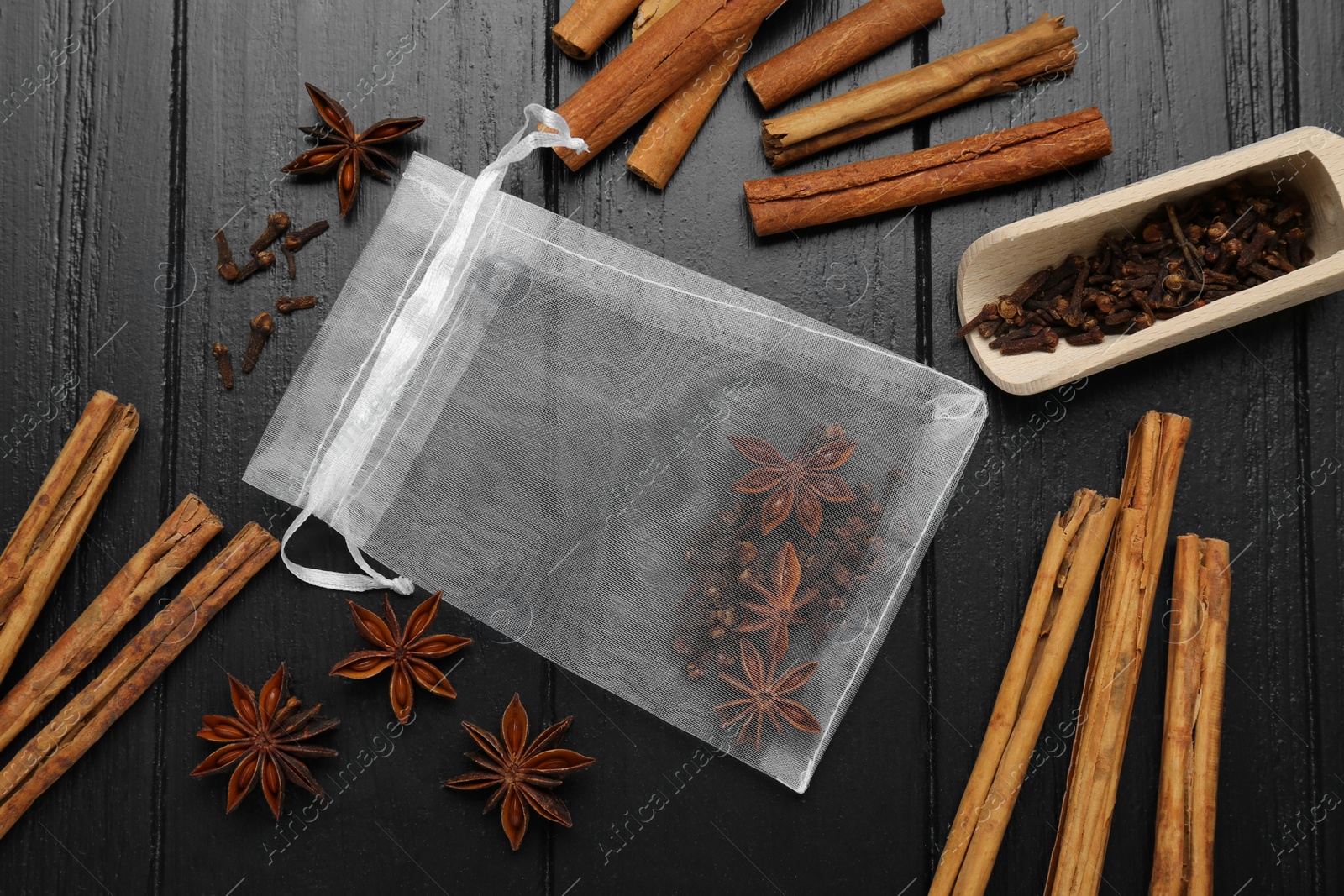 Photo of Scented sachet with cinnamon sticks and anise stars on wooden table, flat lay