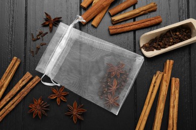 Photo of Scented sachet with cinnamon sticks and anise stars on wooden table, flat lay