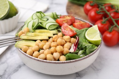 Tasty salad with chickpeas and vegetables on white marble table, closeup