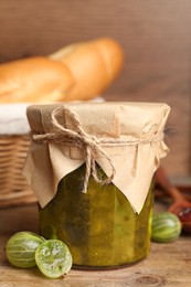 Jar of delicious gooseberry jam and fresh berries on wooden table, closeup