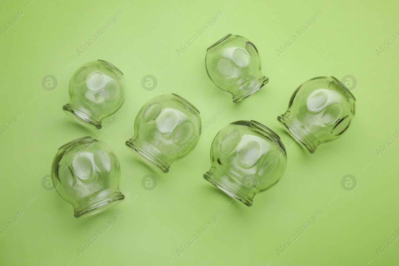 Photo of Glass cups on light green background, flat lay. Cupping therapy