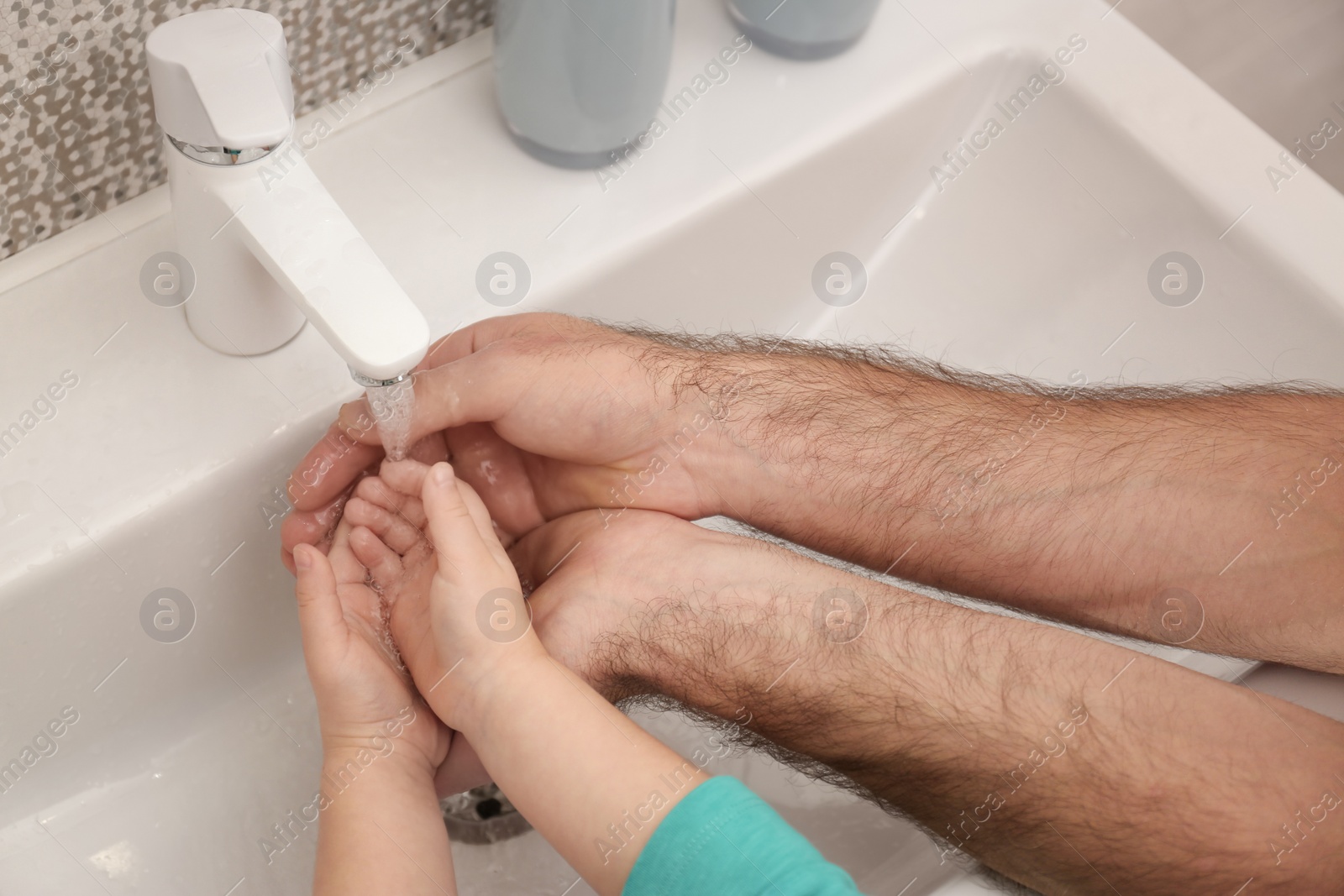 Photo of Father and daughter washing hands in bathroom at home, closeup