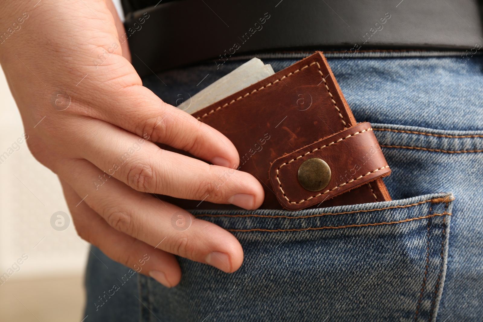 Photo of Man putting wallet with money into pocket of jeans, closeup