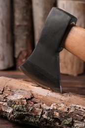Metal axe in wooden log on table, closeup