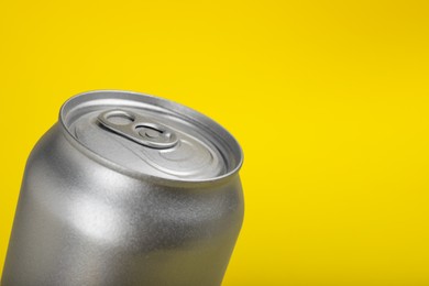 Can of energy drink on yellow background, closeup. Space for text