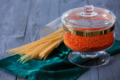 Photo of Red lentil and spaghetti on blue wooden table. Foodstuff for modern kitchen