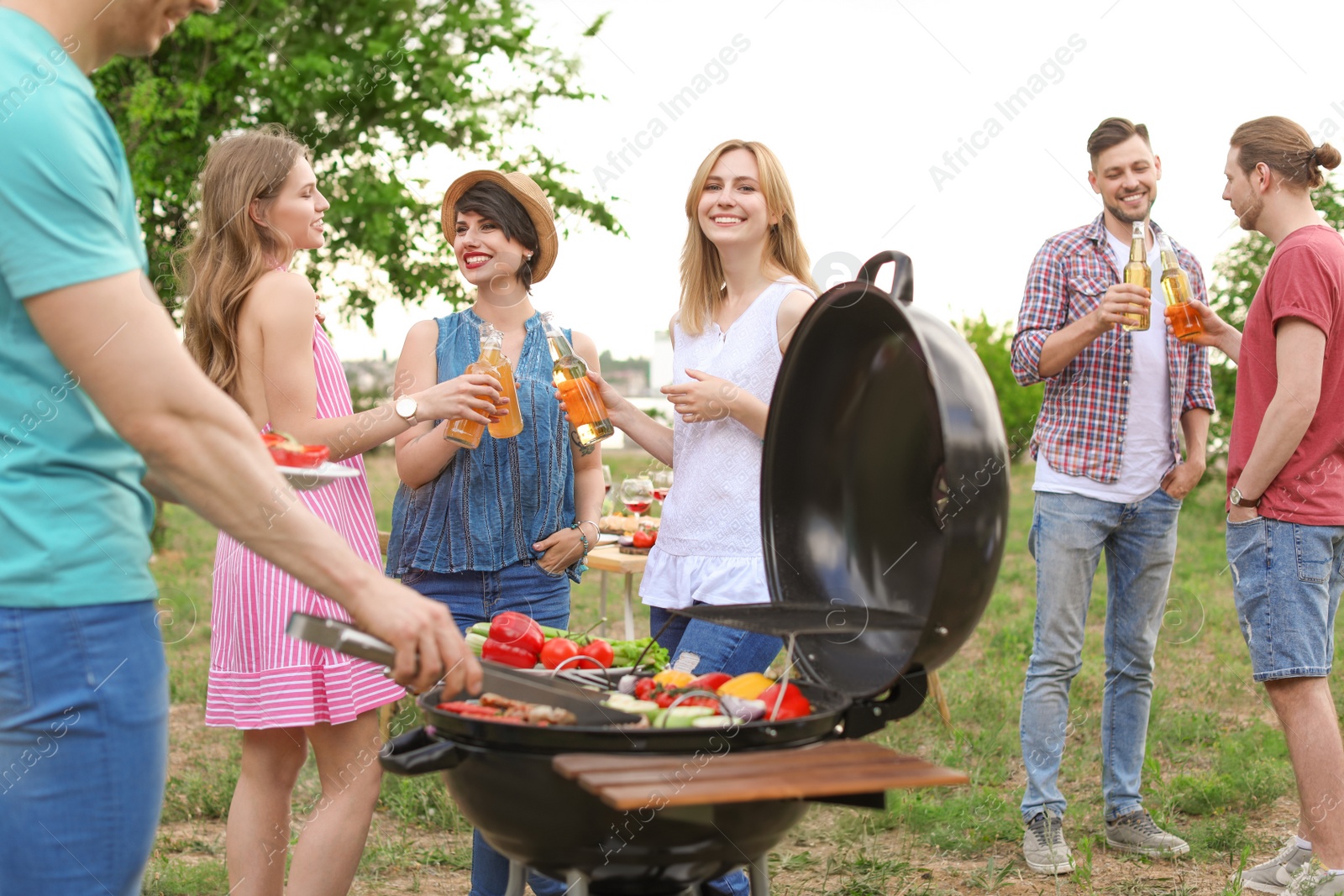 Photo of Young people having barbecue with modern grill outdoors