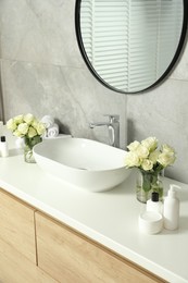 Photo of Beautiful roses and bath accessories near sink in bathroom