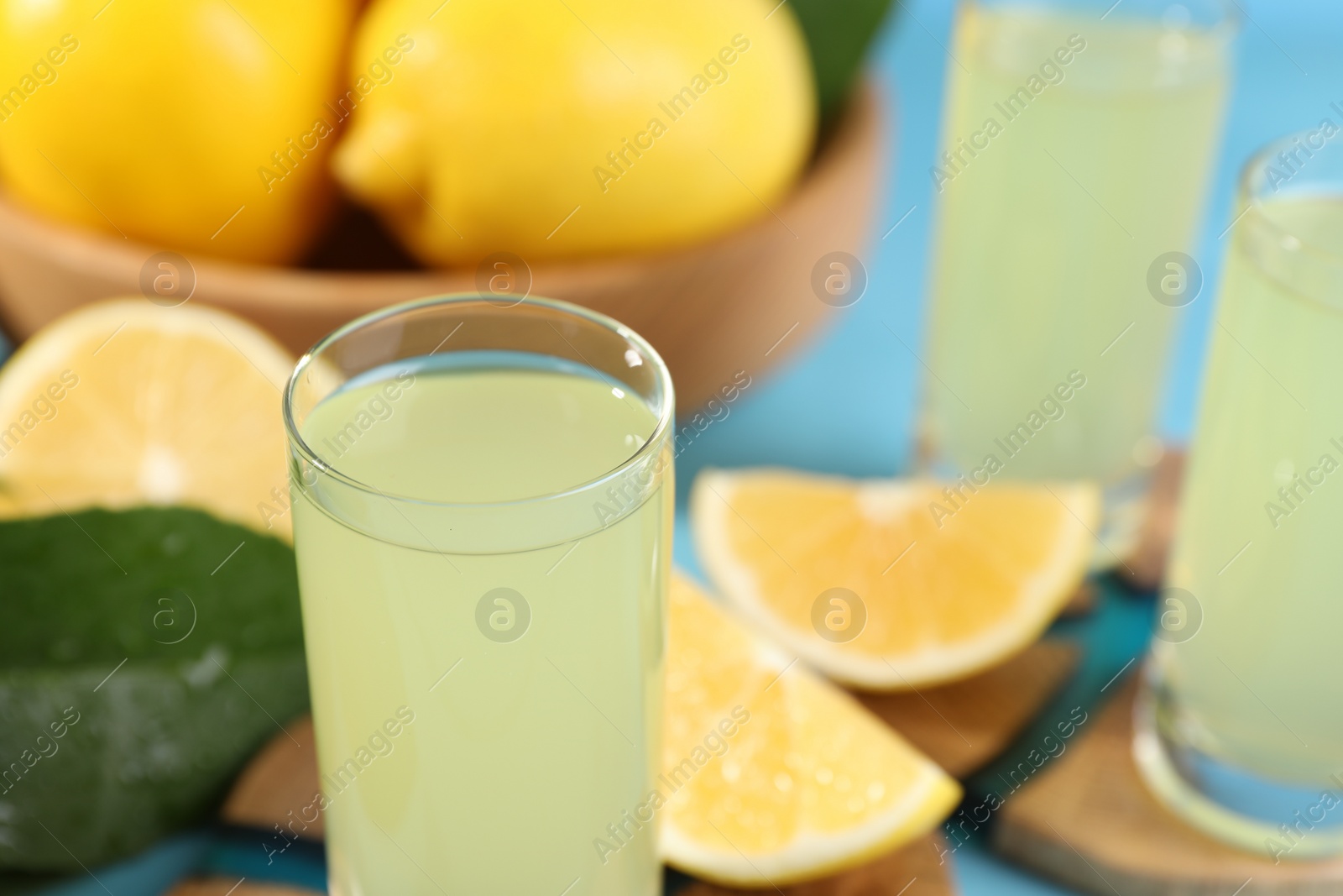 Photo of Tasty limoncello liqueur and lemons on table, closeup. Space for text