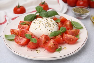 Photo of Tasty salad Caprese with mozarella, tomatoes and basil on light table, closeup