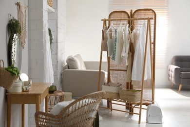 Photo of Rack with stylish women's clothes and dressing table in room. Interior design