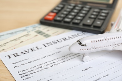 Composition with toy plane, calculator and travel insurance form on table