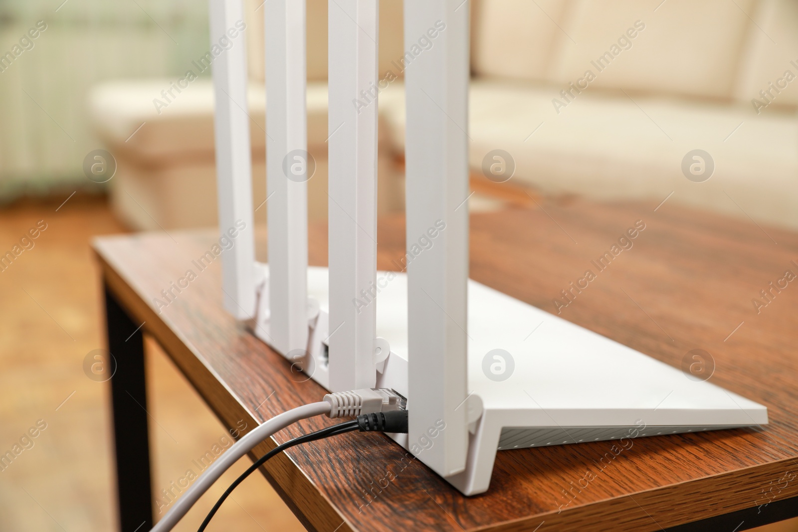 Photo of New modern Wi-Fi router on wooden table indoors, closeup