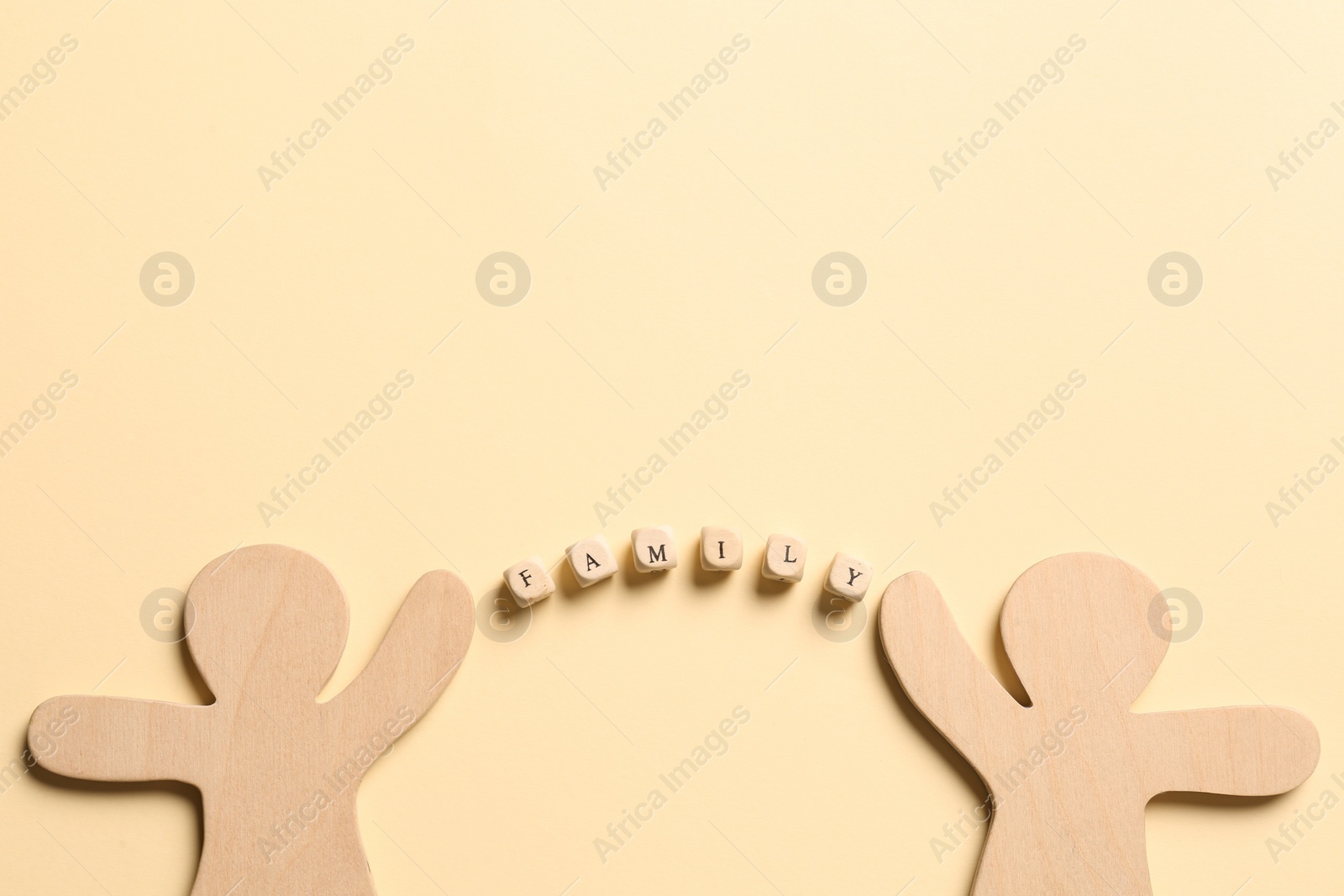 Photo of Wooden figures joined by word Family made of cubes with letters on pale yellow background, flat lay. Space for text