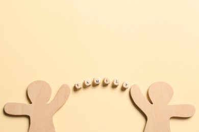 Photo of Wooden figures joined by word Family made of cubes with letters on pale yellow background, flat lay. Space for text
