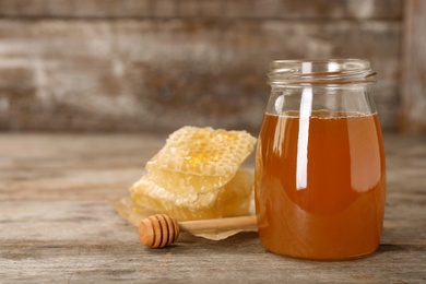 Photo of Jar of tasty fresh honey and dipper on table